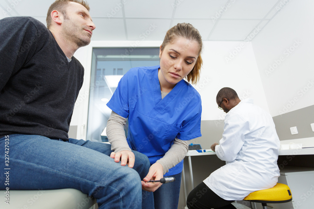 the neurologist testing knee reflex on a patient the neurologist testing knee reflex on a patient