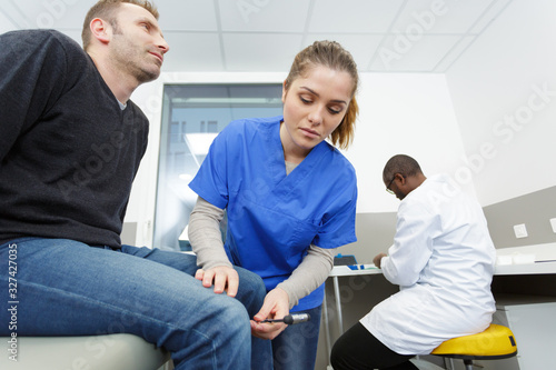 the neurologist testing knee reflex on a patient