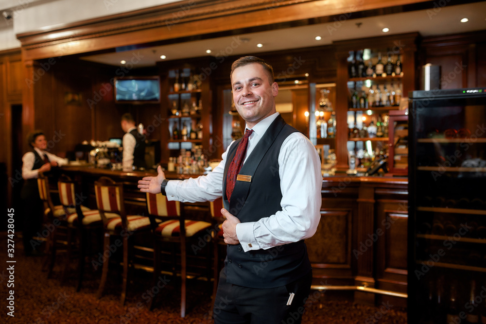 For your enjoyment. Portrait of smiling waiter welcoming guests in hotel restaurant - obrazy, fototapety, plakaty 