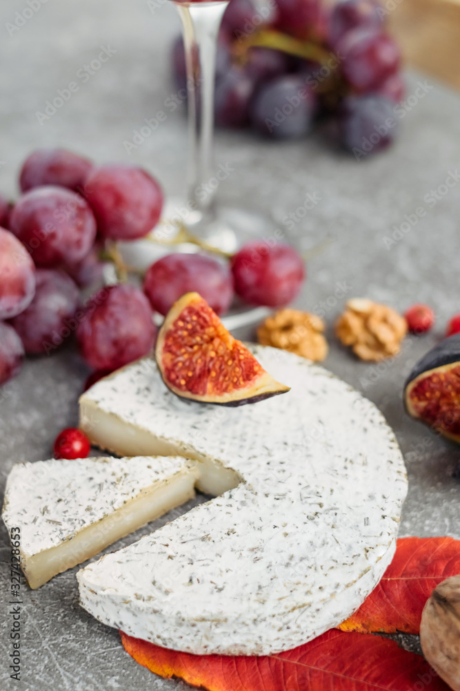 Cheese selection on concrete grey background. Cheese platter with camembert, grapes, nuts.