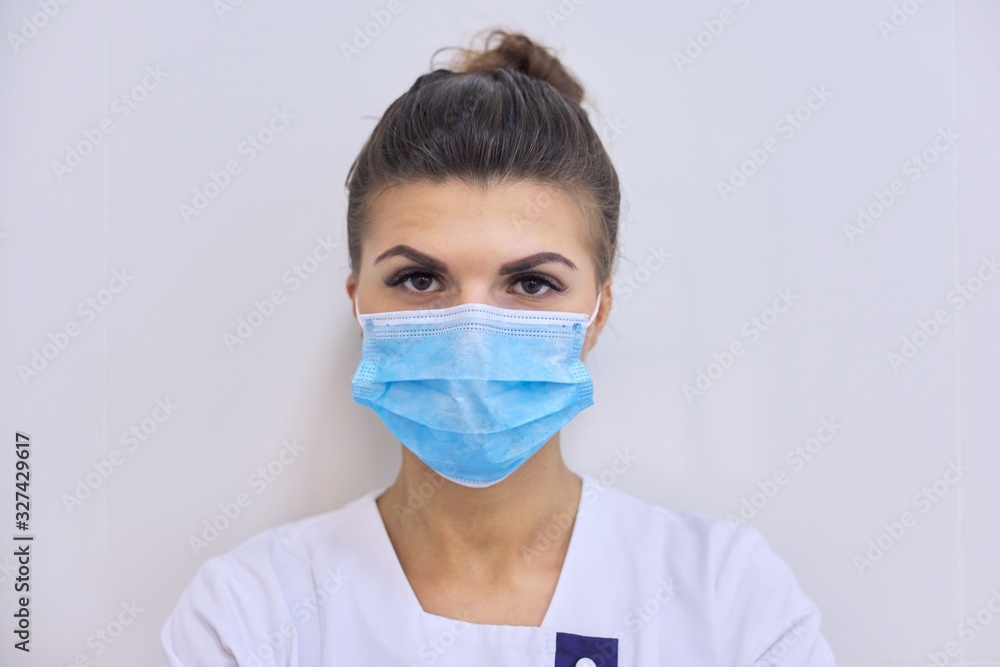 Young serious woman doctor in medical mask looking at camera Young serious woman doctor in medical mask looking at camera