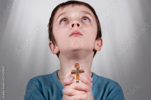 Little boy praying and holding rosary. Hands folded in prayer concept for faith,spirituality and religion.