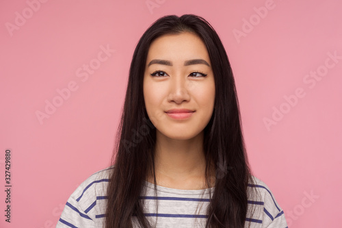 Closeup portrait of funny positive girl with brunette hair in striped t-shirt making silly face with crossed eyes and smiling, looking childish cute. indoor studio shot isolated on pink background photo