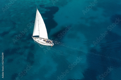 Aerial drone photo of beautiful sail boat cruising in tropical exotic island bay resembling a blue lagoon