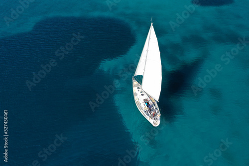 Aerial drone photo of beautiful sail boat cruising in tropical exotic island bay resembling a blue lagoon