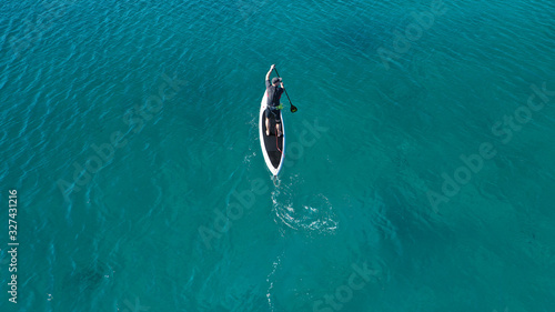 Aerial drone photo of fit man practising Stand Up Paddle or SUP in tropical exotic bay with emerald sea © aerial-drone
