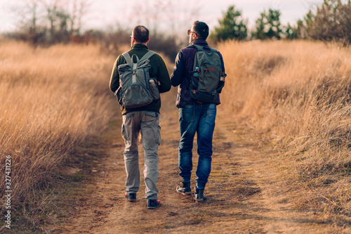 Two men with backpacks hiking on countryside