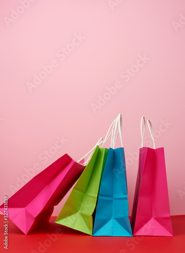 Four empty multicolored paper bags for shopping and gifts with white handles