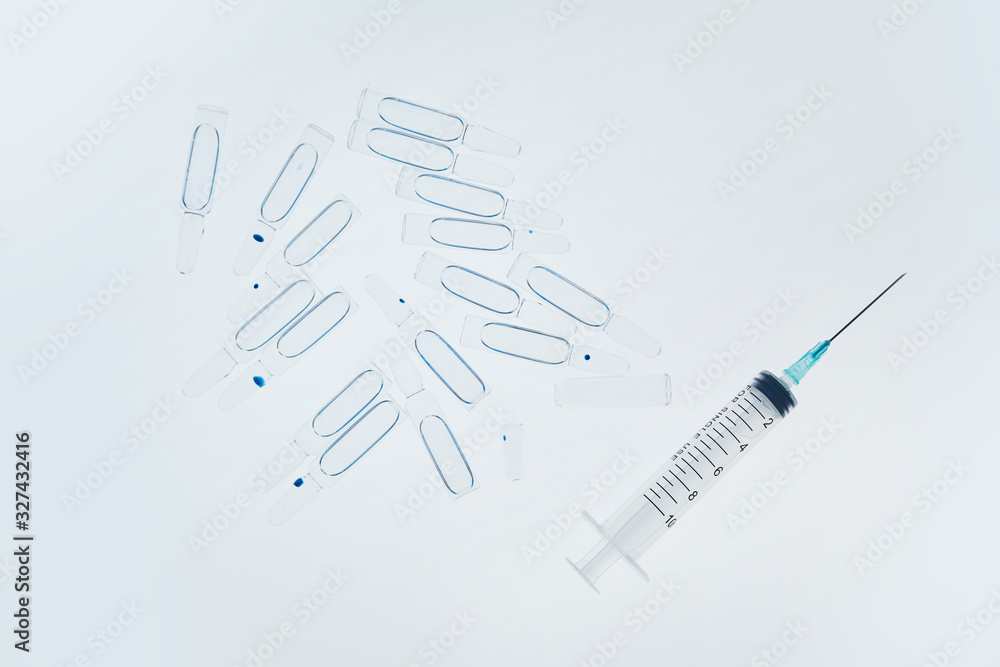 Top view background image of syringe and glass ampules scattered on white table in medical laboratory, copy space Top view background image of syringe and glass ampules scattered on white table in medical laboratory, copy space