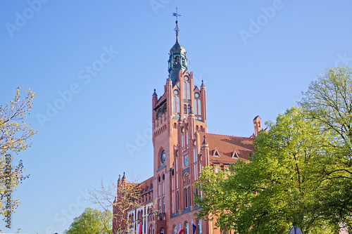 City hall in Slupsk on spring with trees. Town hall old building made of brick.