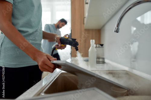 Φωτογραφία Cropped photo of a woman in uniform cleaning filters for kitchen range hood with