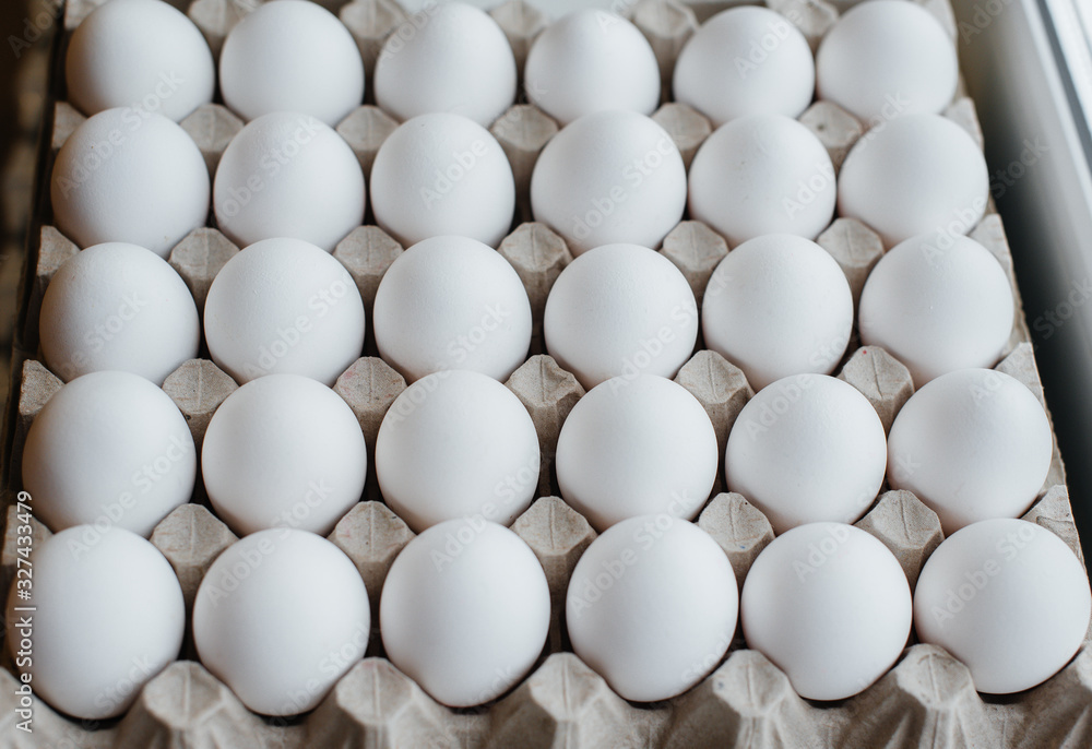 Tray of white fresh eggs close-up on a cardboard form. Agricultural industry Tray of white fresh eggs close-up on a cardboard form. Agricultural industry
