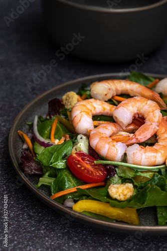 Fresh shrimp and greens salad on dark background