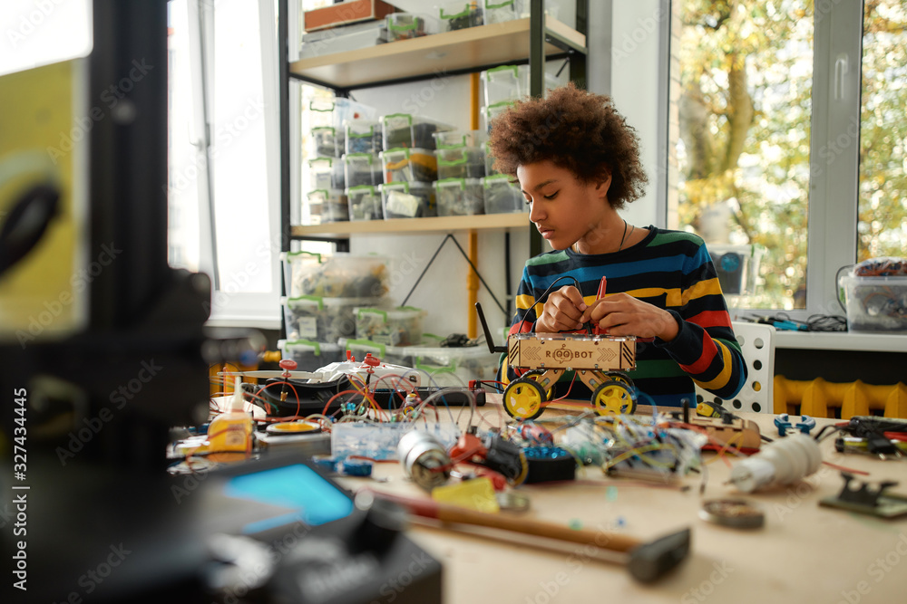 Passion in Every Work. Child programming, testing robot vehicle, working with wires and circuits at stem class.