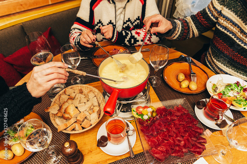 Friends eating cheese fondue in a cozy traditional swiss restaurant