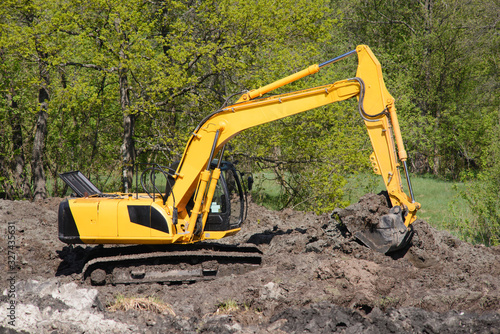 Excavator at construction road near forest in countryside