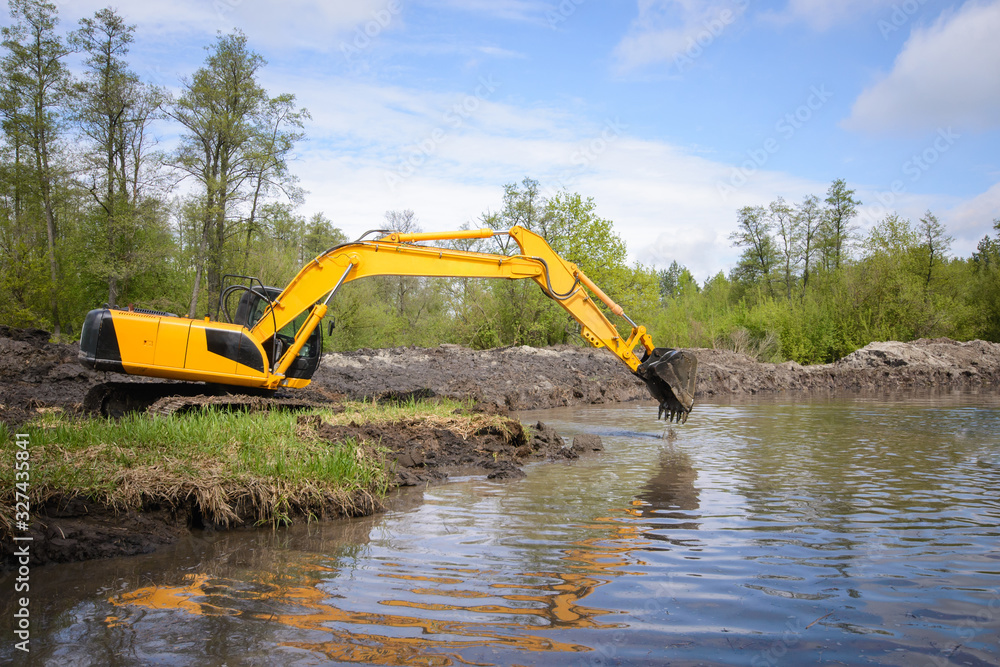 Excavator near small river or pond in countryside. Cleaning river from garbage Excavator near small river or pond in countryside. Cleaning river from garbage