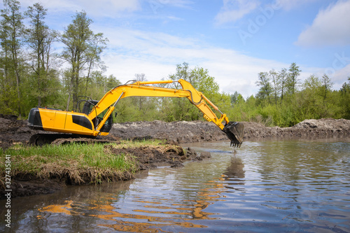 Картината върху платно Excavator near small river or pond in countryside