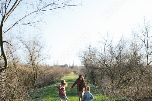 Happy family spending time outdoors playing n the lawn. Mom having fun with two kids. Family values