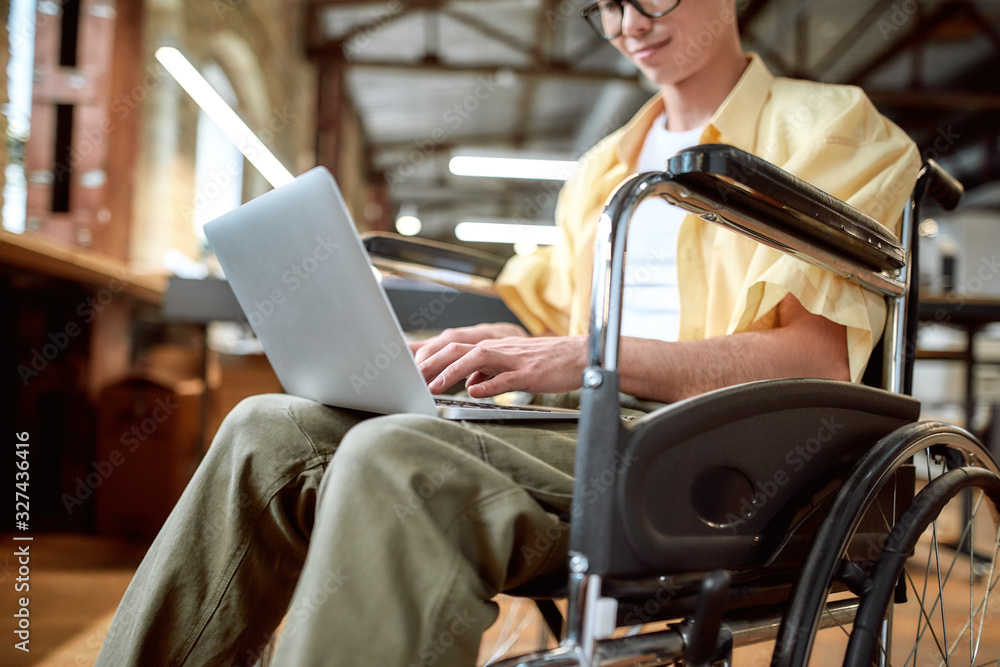 Everyone is needed. Guy in a wheelchair working in the office Everyone is needed. Guy in a wheelchair working in the office