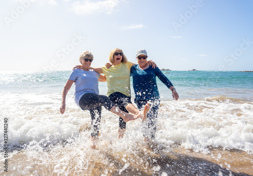 Group of three senior women walking having having fun on beach. Friendship and healthy lifestyle