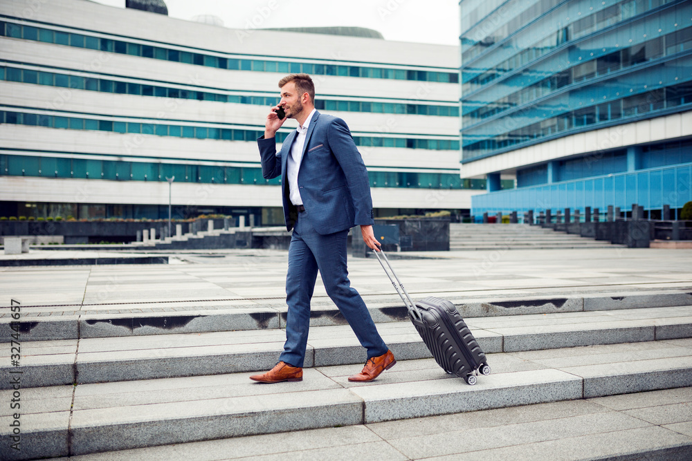 Handsome young businessman walking with suitcase Handsome young businessman walking with suitcase