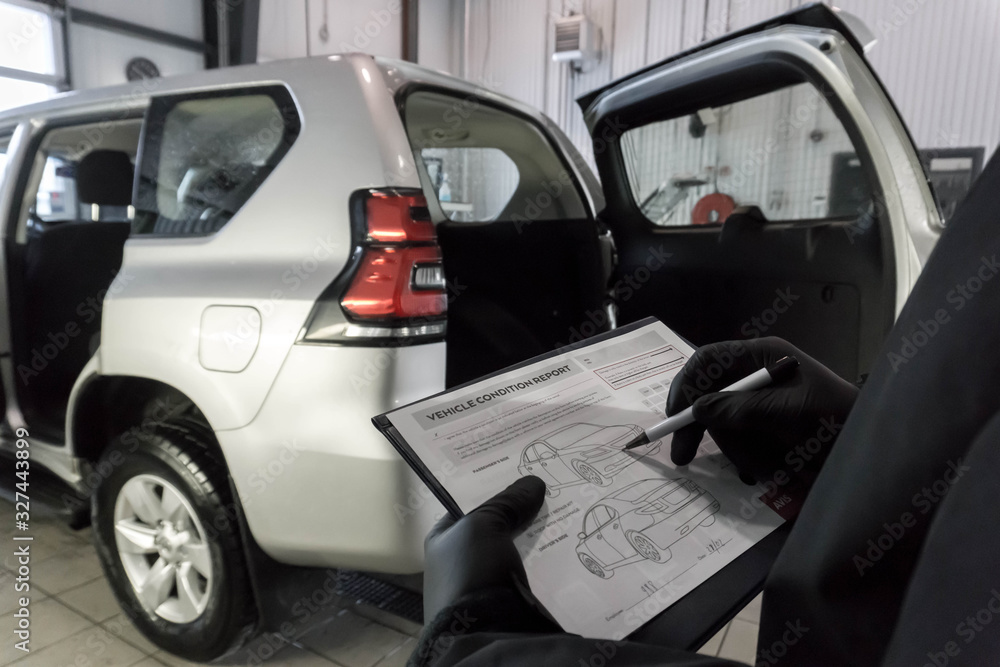 Man inspecing vehicles condition and making a condition report, marking it on a clipboard Man inspecing vehicles condition and making a condition report, marking it on a clipboard