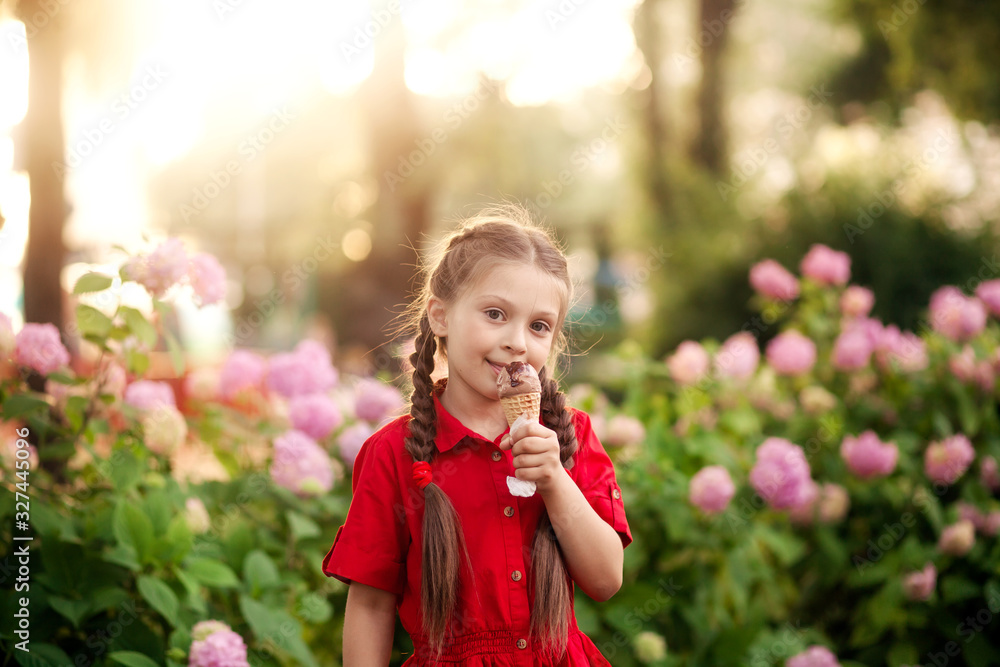 pretty cute girl in a red dress eating ice cream in the park on a summer evening pretty cute girl in a red dress eating ice cream in the park on a summer evening