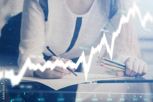 Double exposure of hands making notes with forex chart huds. Stock market concept.