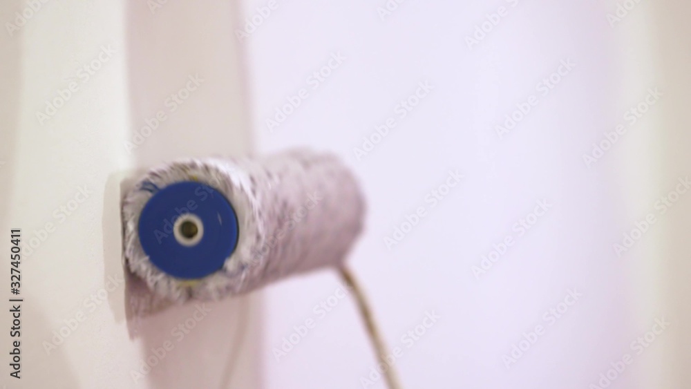 Young asian happy woman painting interior wall with paint roller in new house Young asian happy woman painting interior wall with paint roller in new house