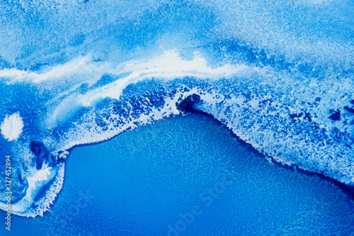 Classical blue and white watercolor paint in abstract flowing shapes similar to satellite imagery with arctic snow hills, coastline and ocean with glaciers melting in macro. Stains of paint design.