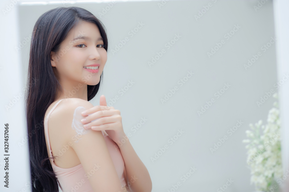 Beautiful sexy young asian woman look mirror applying cream on shoulder and message, beauty girl applying body lotion skin care for health and soft hydration, treatment and cosmetic with moisturizer. Beautiful sexy young asian woman look mirror applying cream on shoulder and message, beauty girl applying body lotion skin care for health and soft hydration, treatment and cosmetic with moisturizer.