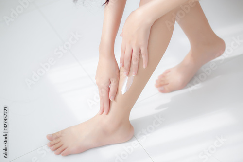 Beautiful asian woman touch skin leg smooth with cream and lotion for hydration and smooth, girl applying body care and cosmetic for silky and soft, beauty perfect with wellness, health and care. © N_studio