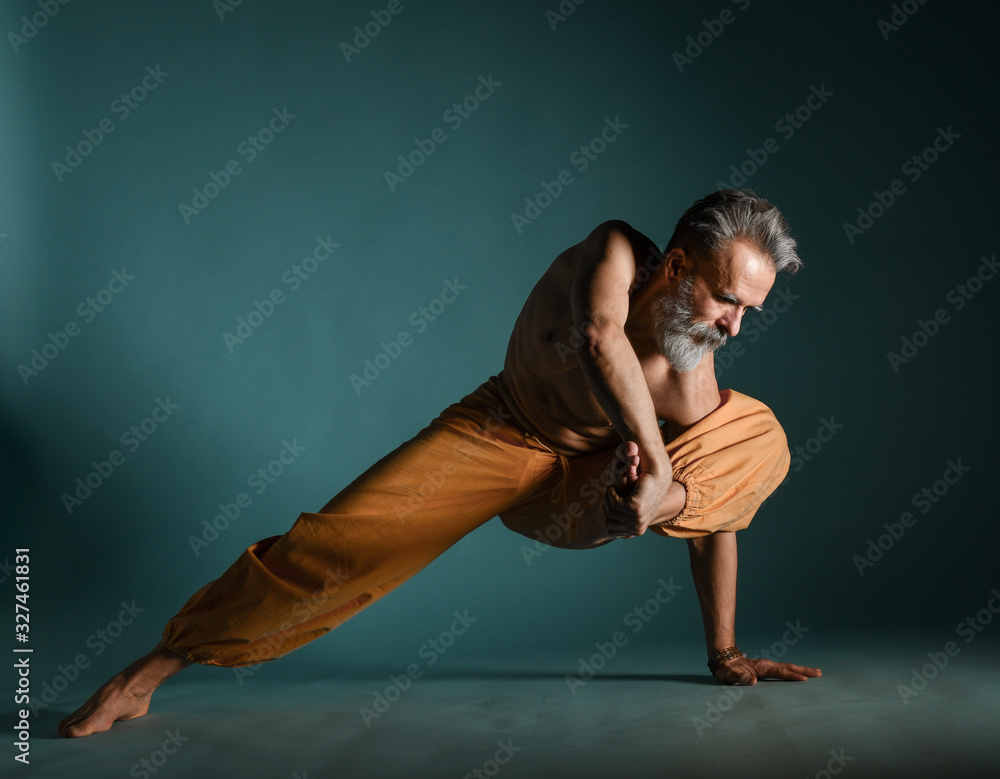 Old man with grey beard doing yoga, pilates, fitness training, stretching exercise, asana or balance workout on floor