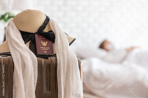 Hat and Passport on lugguage with sick woman wearing face protection mask lying on bed has fever by corona virus 2019 or COVID-19 after travel from China,Coronavirus Concept photo