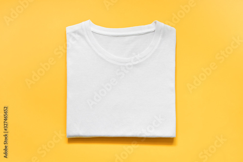 top view of folded white color t-shirt on yellow background, copy space, flat lay