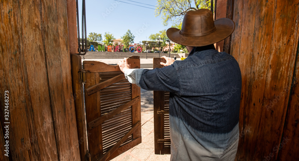 Historic center of Amealco, Querétaro, Mexico, with its traditional canteens with its typical doors of the old west, with a cowboy dressed tourist leaving the canteen going to the main square 2 Historic center of Amealco, Querétaro, Mexico, with its traditional canteens with its typical doors of the old west, with a cowboy dressed tourist leaving the canteen going to the main square 2
