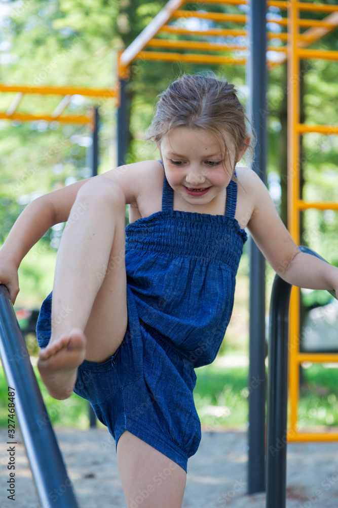 Fototapeta premium Young girl in a blue dress on a playground