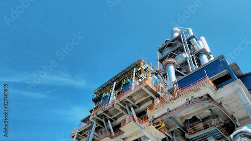 Looking up view of newly built cement plant with preheater tower against blue sky
