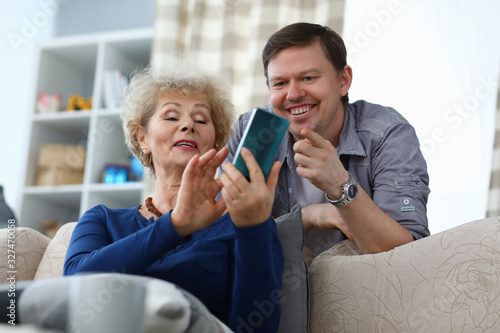 Obraz na plátně Elderly mother shows photo in phone to adult son