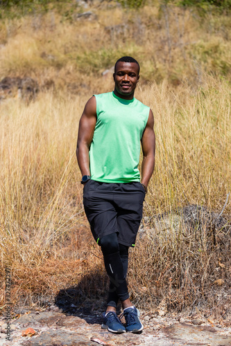 portrait, african man in sportswear smiling standing in summertime nature background.