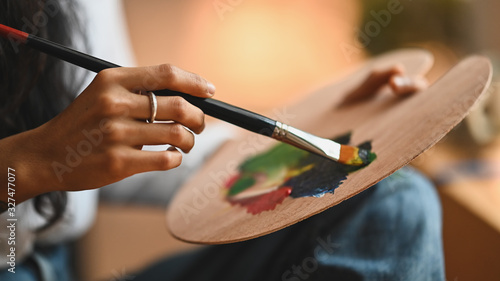 Cropped image of artist woman's hand drawing an oil color on canvas by paint brush at the modern art studio. Young artist/Painter concept.