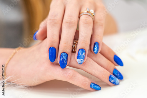 Hands of a girl with a beautiful blue manicure are on display. blue glossy nail