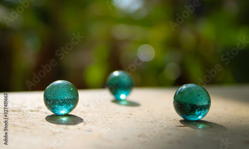 A transparent glass with green marbles on the top of the wall with a good blur background with a creative concept and  text area space.