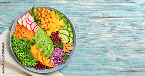 Buddha bowl salad with avocado, tomato, lettuce, cucumber, red cabbage, chickpeas, pomegranate. Paleo diet, healthy vegan and balanced food concept. Fresh rainbow mix green salad on blue wood