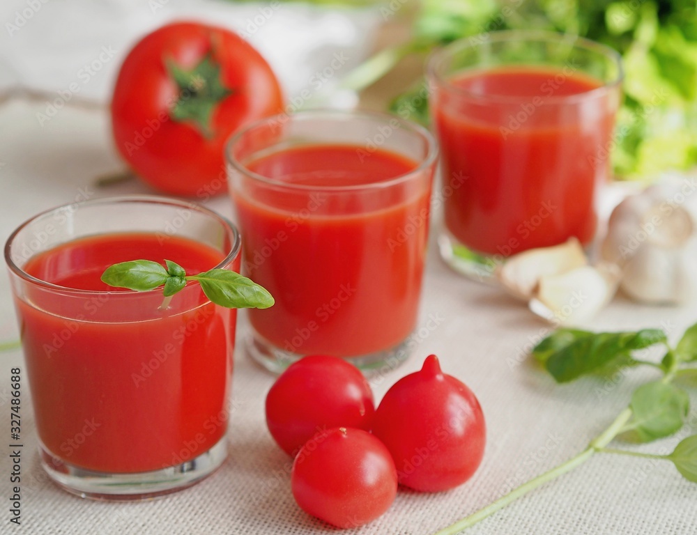 Three glasses with tomato juice decorated with basil. Selective focus Three glasses with tomato juice decorated with basil. Selective focus