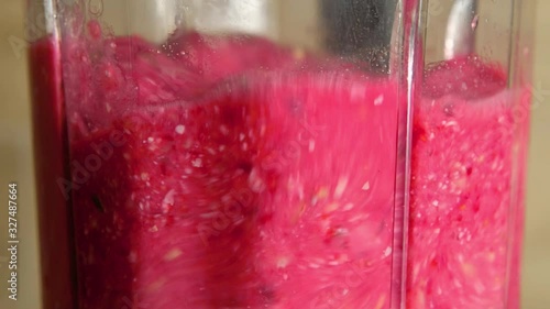 Blender with raspberries and banana is making smoothie. Blender with healthy fruit mixture. Close up
