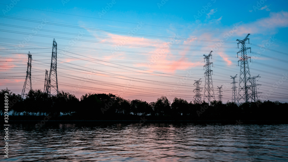 High voltage electrical tower and beautiful river nature landscape at sunset