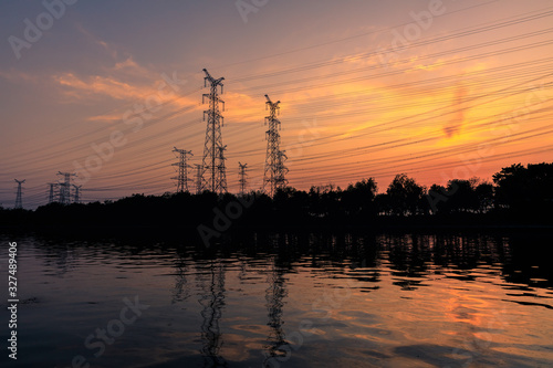 High voltage electrical tower and beautiful river nature landscape at sunset