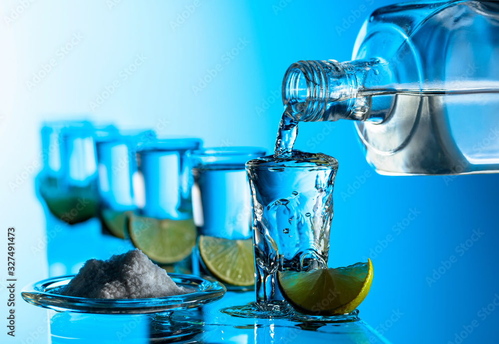 Tequila, salt and lime slices on a blue background. Tequila, salt and lime slices on a blue background.